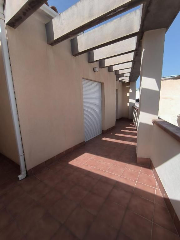 Un pasillo muy largo con una pérgola y una puerta de garaje.