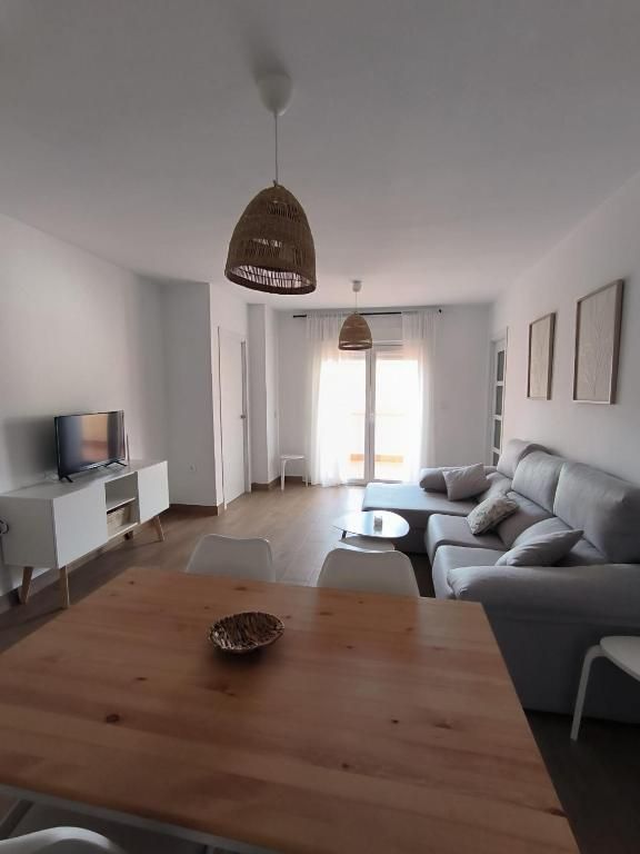 Una sala de estar con sofá, mesa y televisión.