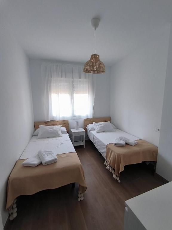 Un dormitorio con dos camas y una lámpara colgando del techo.