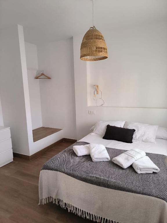 Un dormitorio con una cama y una lámpara colgando del techo.