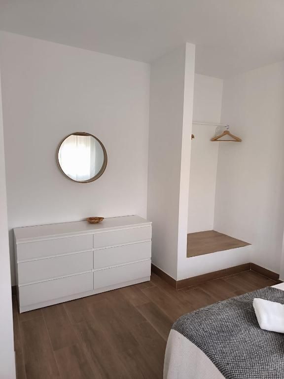 Un dormitorio con cama, tocador y espejo.