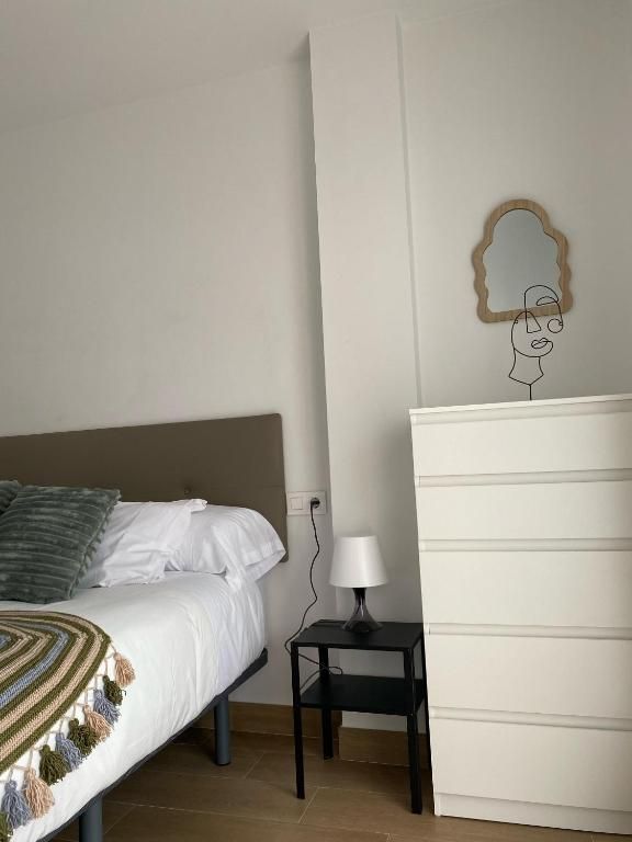 Un dormitorio con una cama, una cómoda y un espejo.