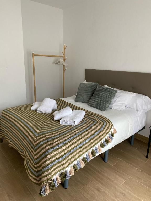 Una cama con una manta a rayas y almohadas en un dormitorio.