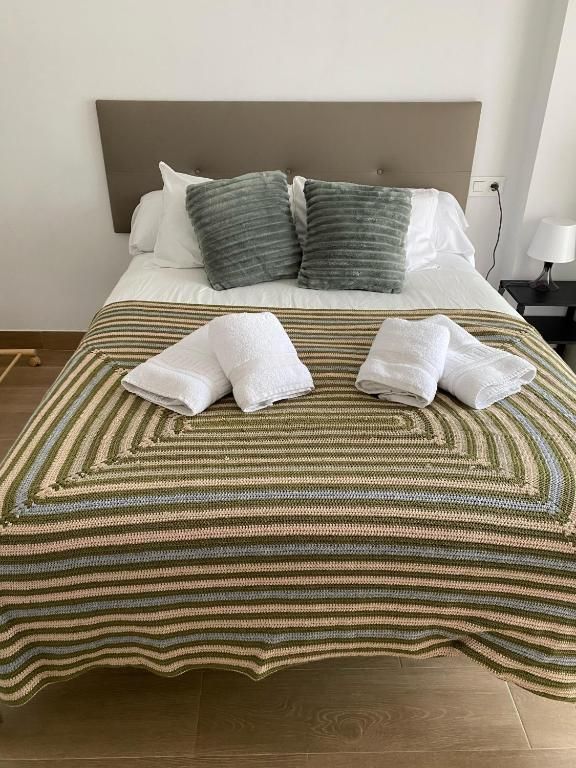 Una cama con una manta a rayas y toallas encima.