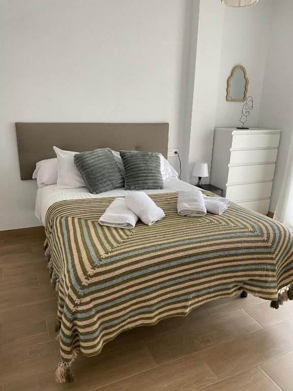 Una cama con una manta a rayas y almohadas en un dormitorio.