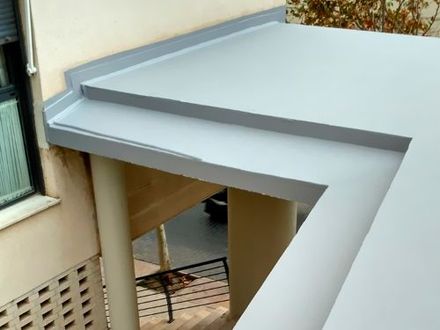 Un balcón con techo gris y escaleras en el costado de un edificio.