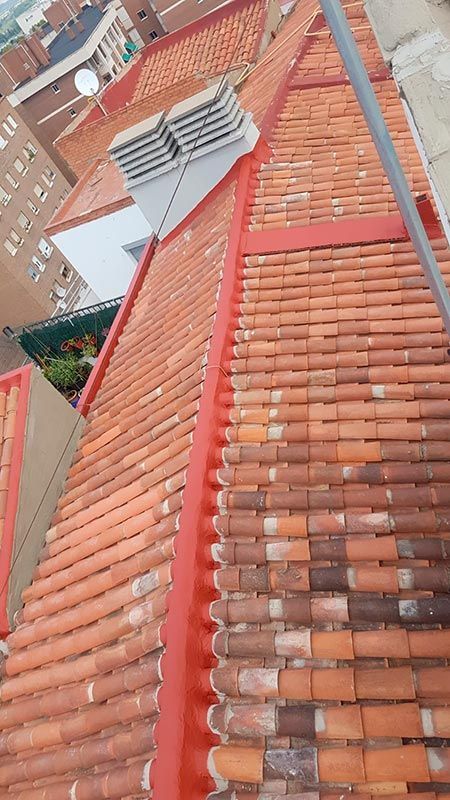 Un techo con tejas rojas y una chimenea encima.