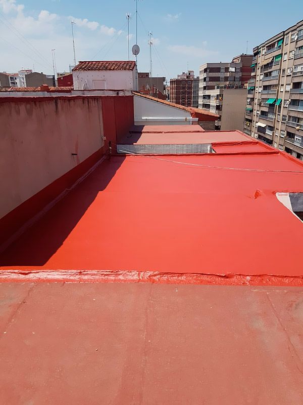 Un techo rojo con muchos edificios al fondo.