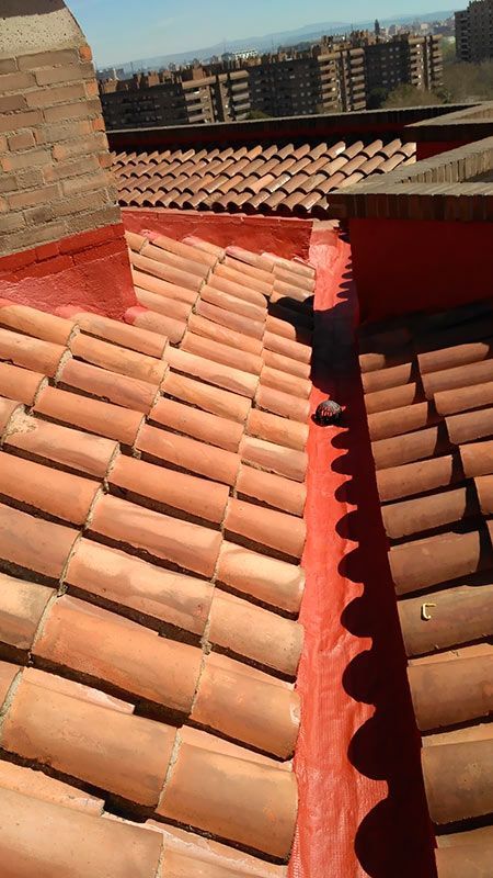 Un techo con tejas rojas y un canalón rojo