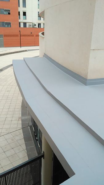 Un edificio con un techo curvo y una valla delante de él.