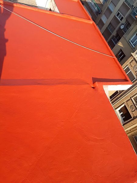 Un techo rojo con la sombra de una persona sobre él.