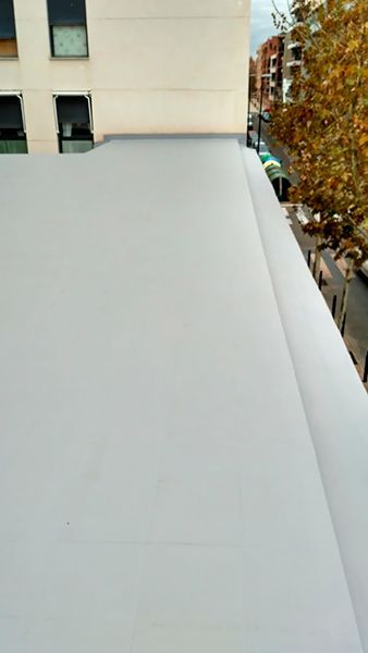 Un primer plano de un techo blanco con un edificio al fondo.