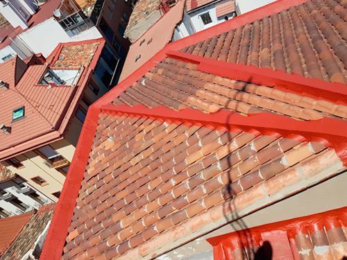 Una vista aérea de un techo de tejas rojas con edificios al fondo.