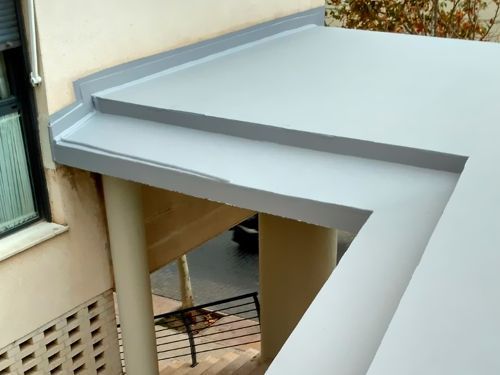 Un balcón con techo gris y escaleras en el costado de un edificio.