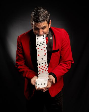 Un hombre con una chaqueta roja sostiene una pila de cartas en sus manos.
