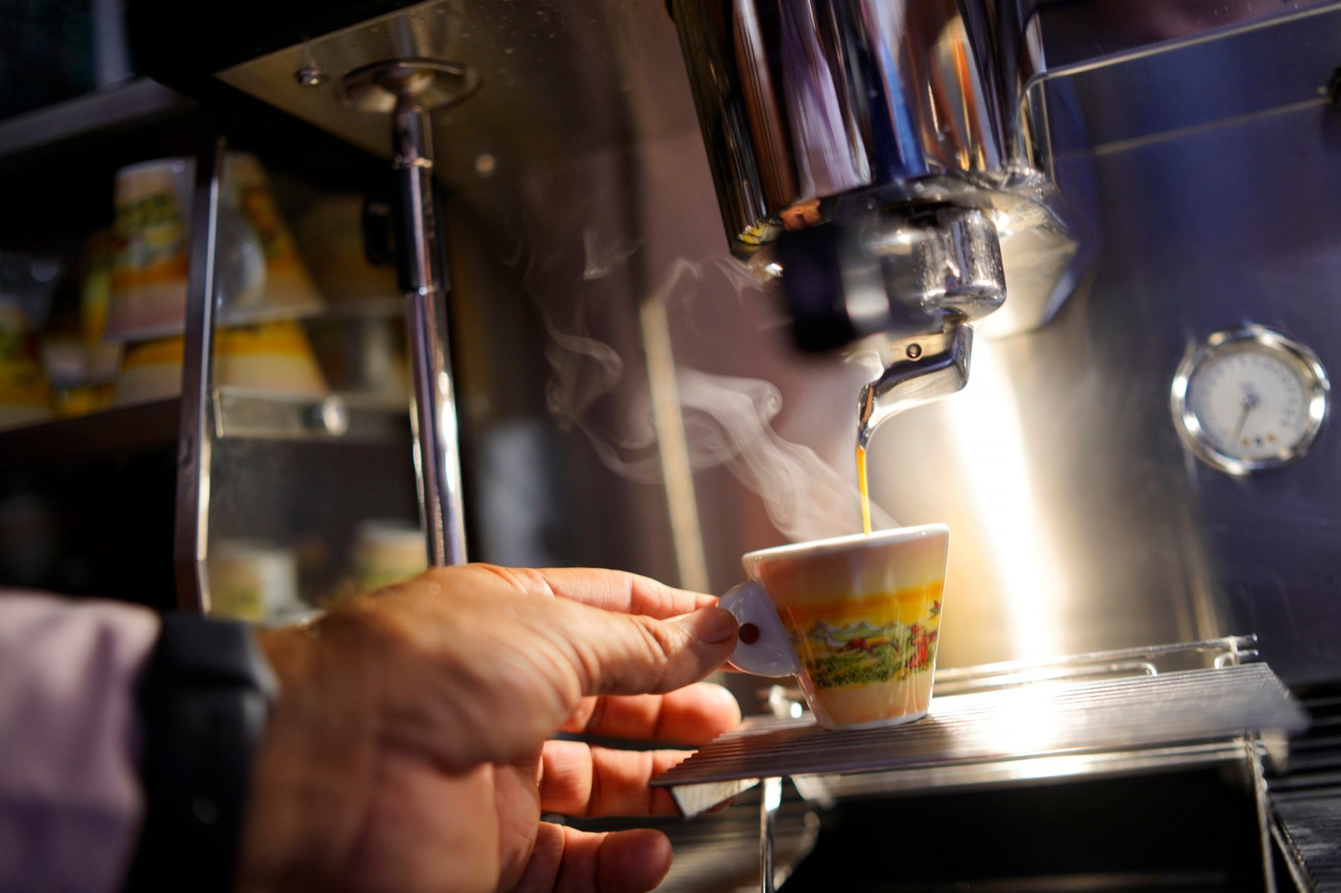 Eine Person schenkt eine Tasse Kaffee aus einer Kaffeemaschine ein.