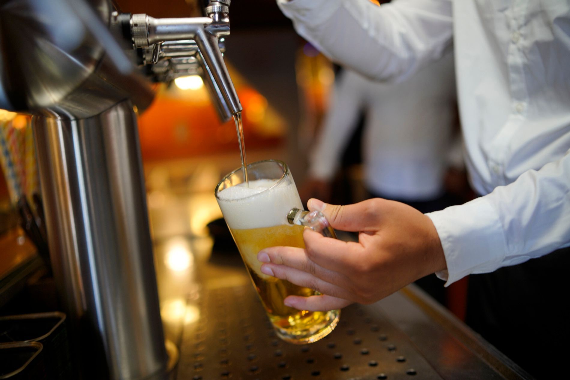 Ein Barkeeper schenkt ein Glas Bier aus einem Zapfhahn ein.