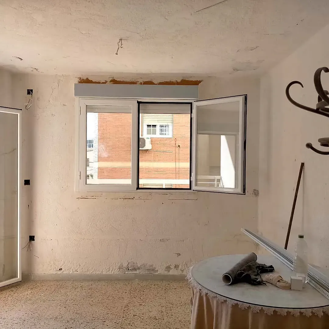 Una habitación vacía con una mesa y una ventana.