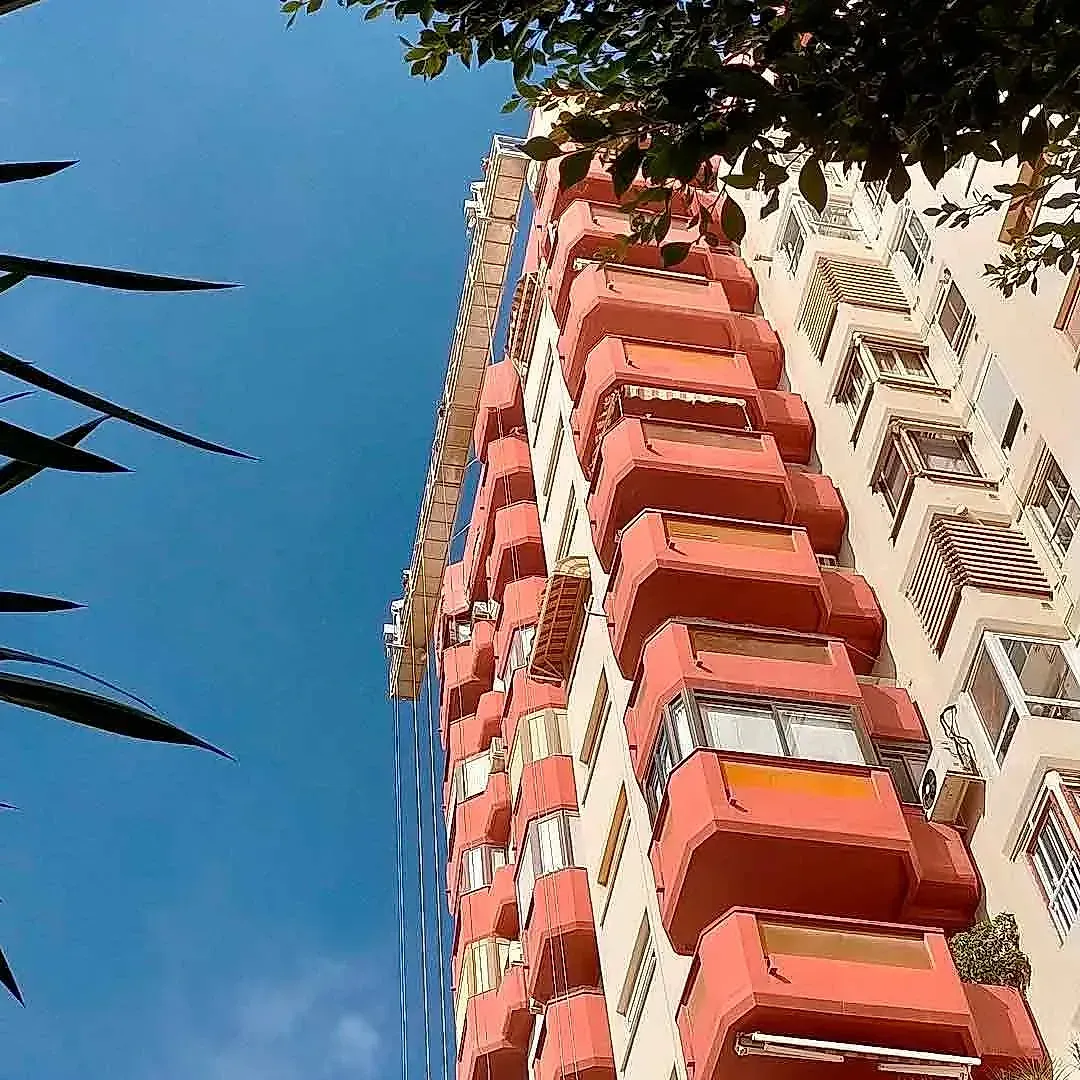 Mirando hacia arriba a un edificio alto con un cielo azul en el fondo