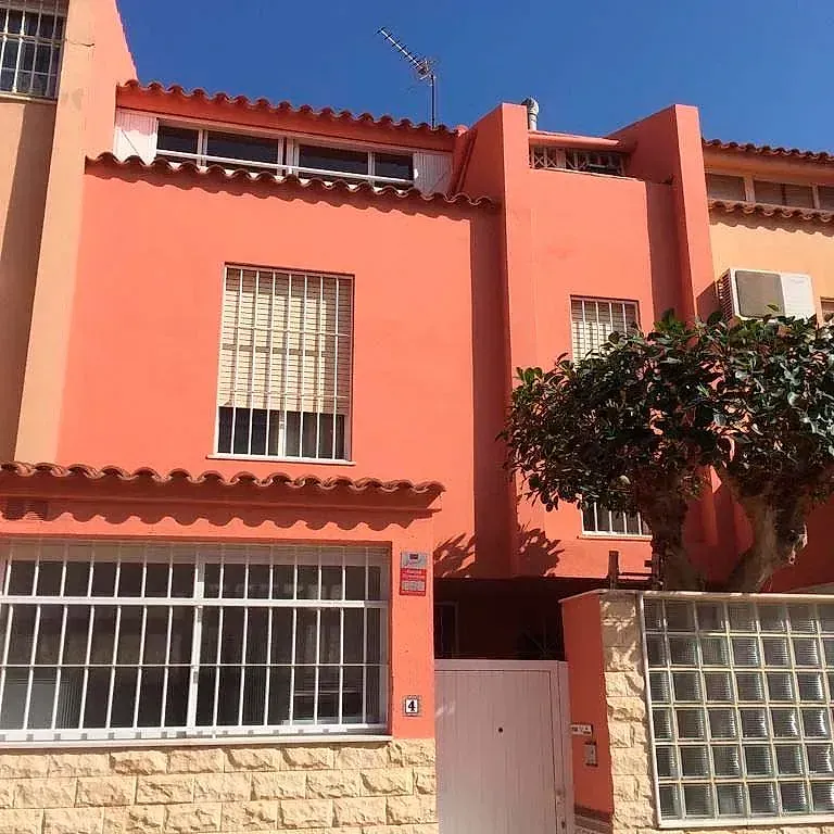 Un edificio rosa con un árbol delante.