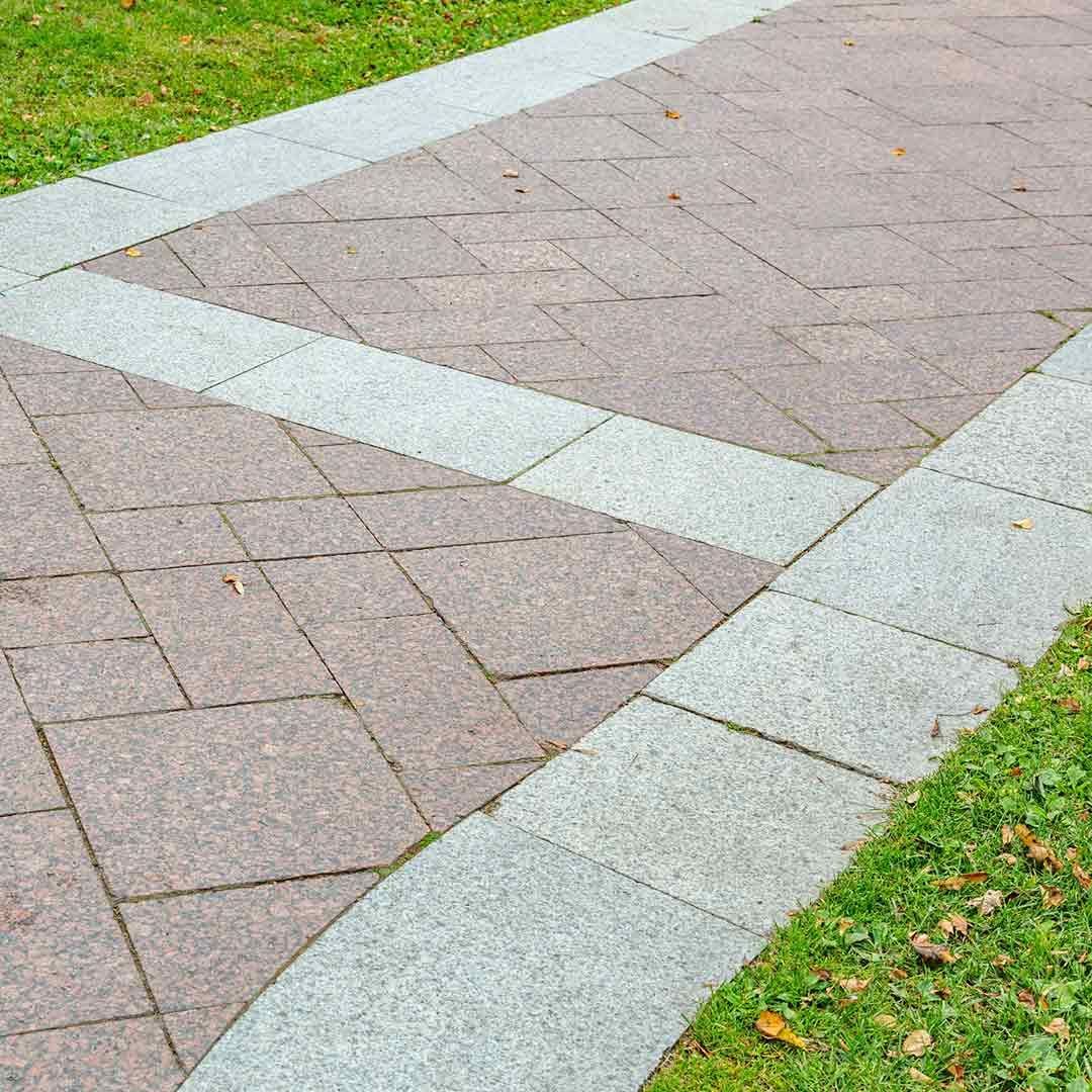 Una pasarela de ladrillos en un parque con césped al costado.