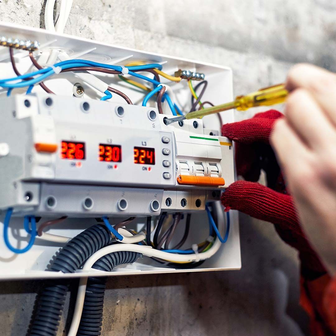 Una persona está trabajando en una caja eléctrica con un destornillador.