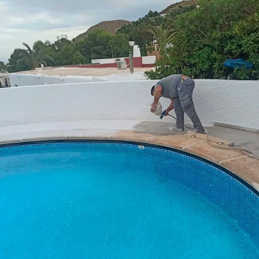 Un hombre está pintando el lateral de una piscina.