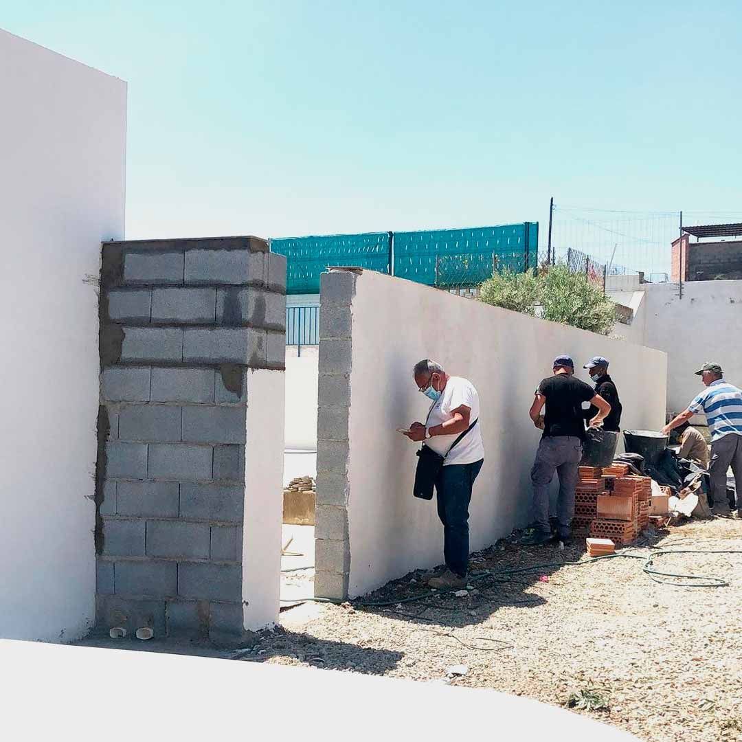 Un grupo de hombres está trabajando en una pared blanca.