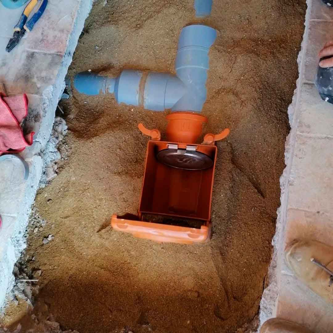 Se está instalando un tubo de drenaje en un agujero en el suelo.