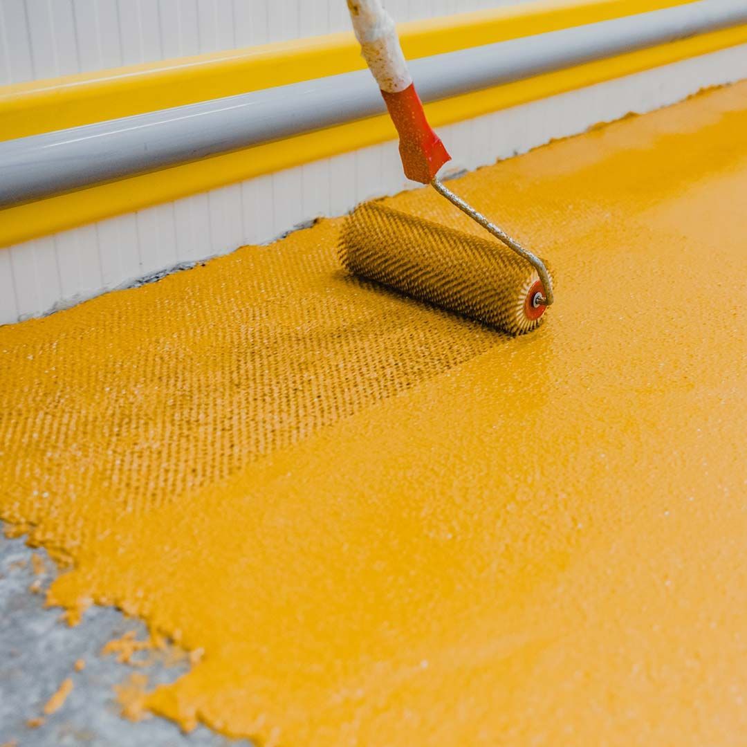 Se está utilizando un rodillo para pintar un piso amarillo.