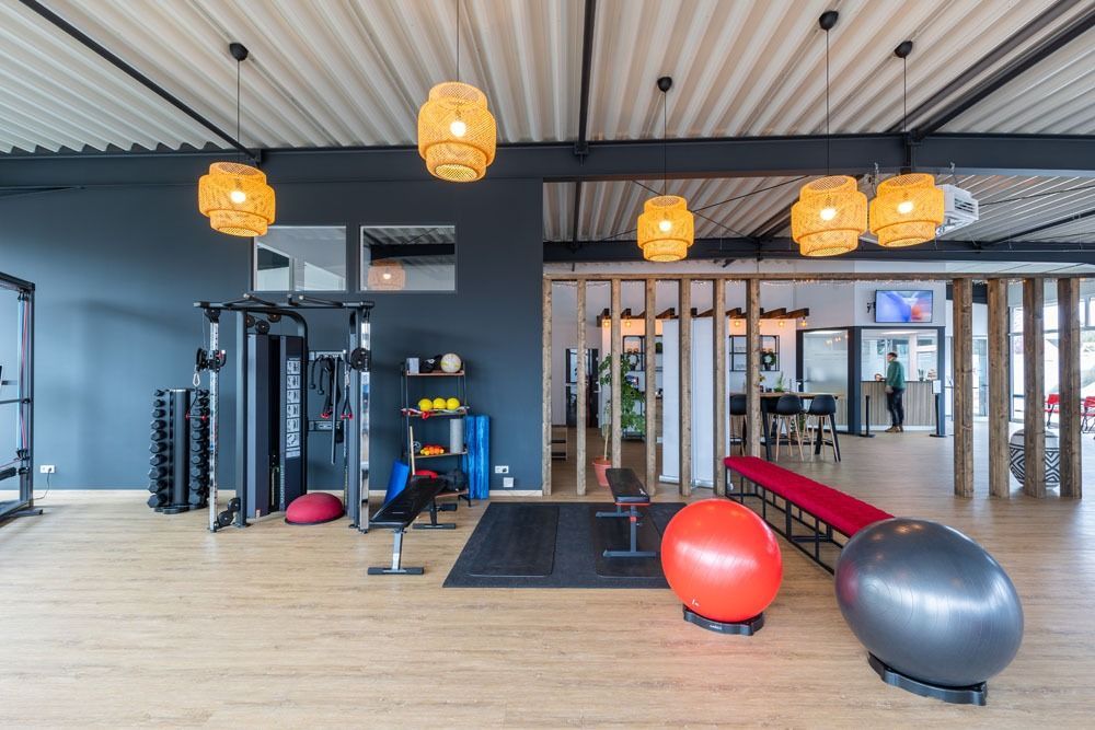 Ein Fitnessstudio mit vielen Geräten und Bällen auf dem Boden