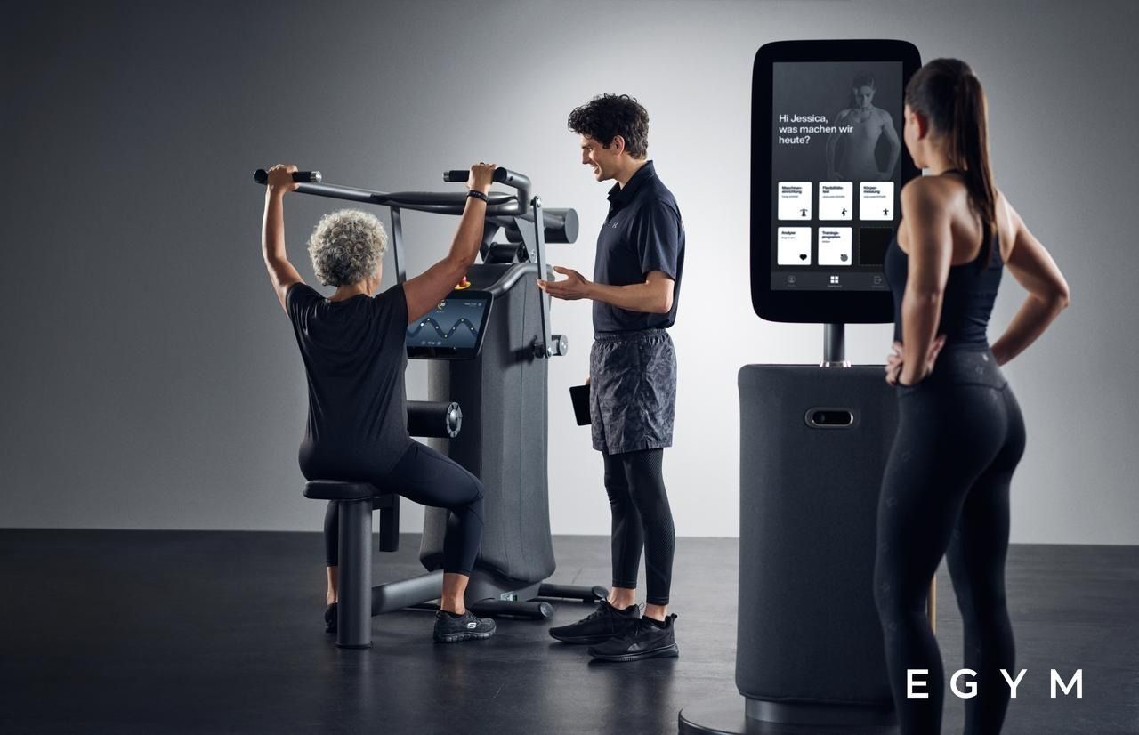 Ein Mann und eine Frau stehen neben einem Gerät in einem Fitnessstudio.