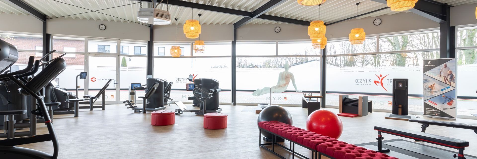 Ein Fitnessstudio mit vielen Trainingsgeräten und einer Bank.