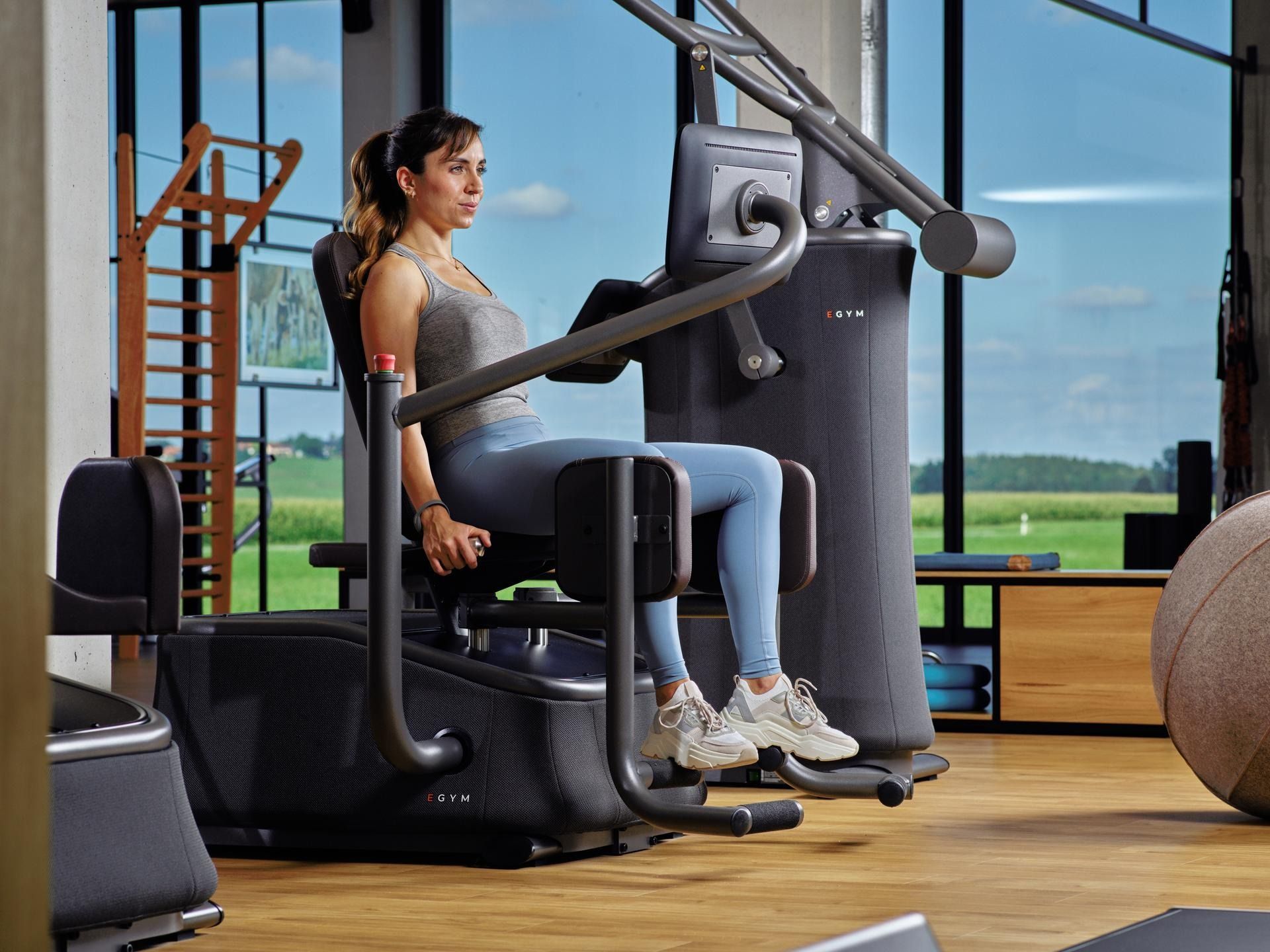Eine Frau sitzt in einem Fitnessstudio auf einem Gerät.
