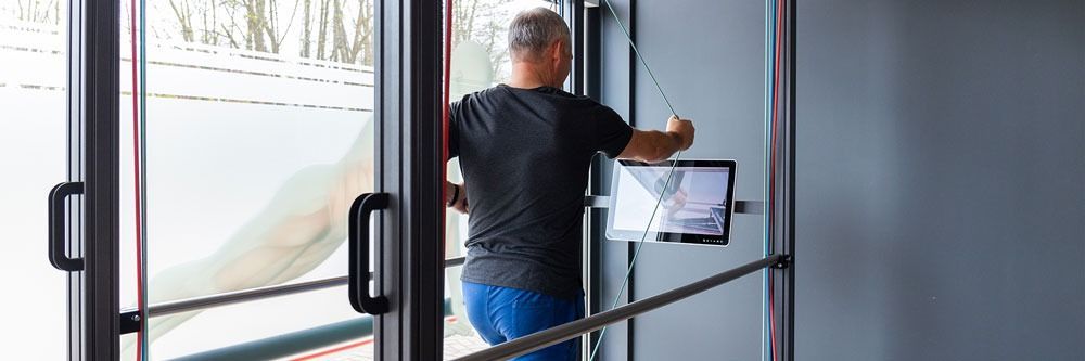 Ein Mann steht in einem Türrahmen und hält ein Tablet in der Hand.