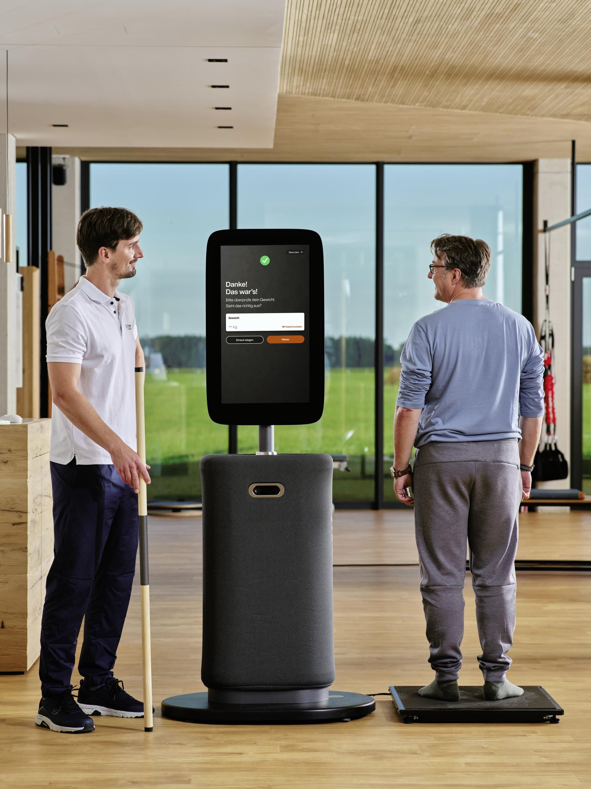 Zwei Männer stehen neben einem Gerät in einem Fitnessstudio.