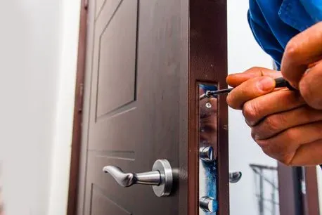 Un hombre está arreglando una puerta con un destornillador.
