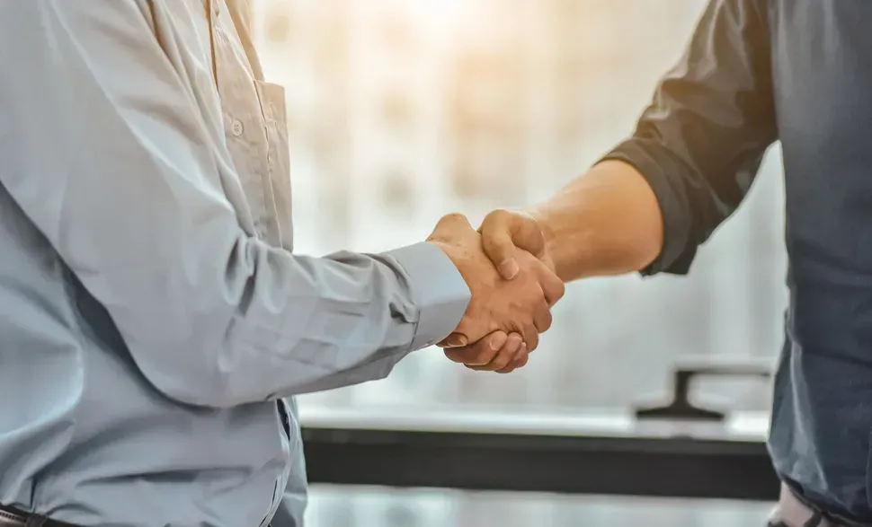 Zwei Männer geben sich in einem Büro die Hand.