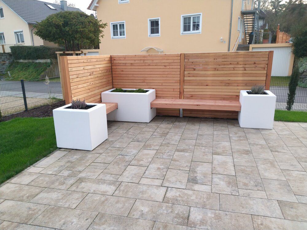 Holzbank mit Pflanzkästen; Terrassenmöbel mit Sichtschutzzaun aus Holz.