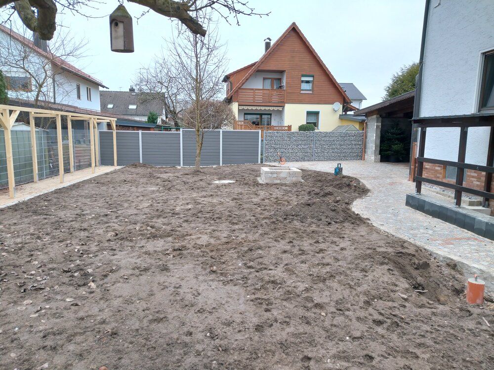 Ein matschiger Hof mit Zaun, im Hintergrund ein Haus und auf der rechten Seite ein Pfad.