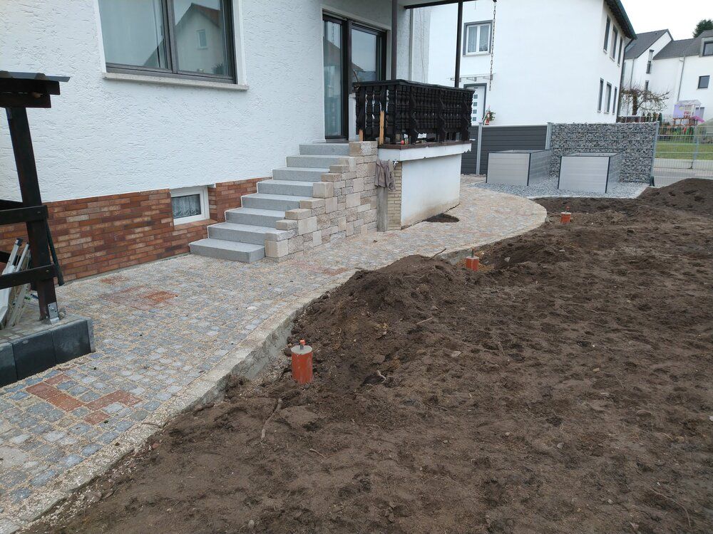 Ein Haus mit einem Steinweg, Stufen und einem unbefestigten Hof, der gerade neu gestaltet wird.