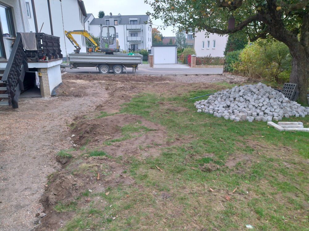 Baustelle: Bagger und Baumaterialien auf dem Rasen neben dem Haus.