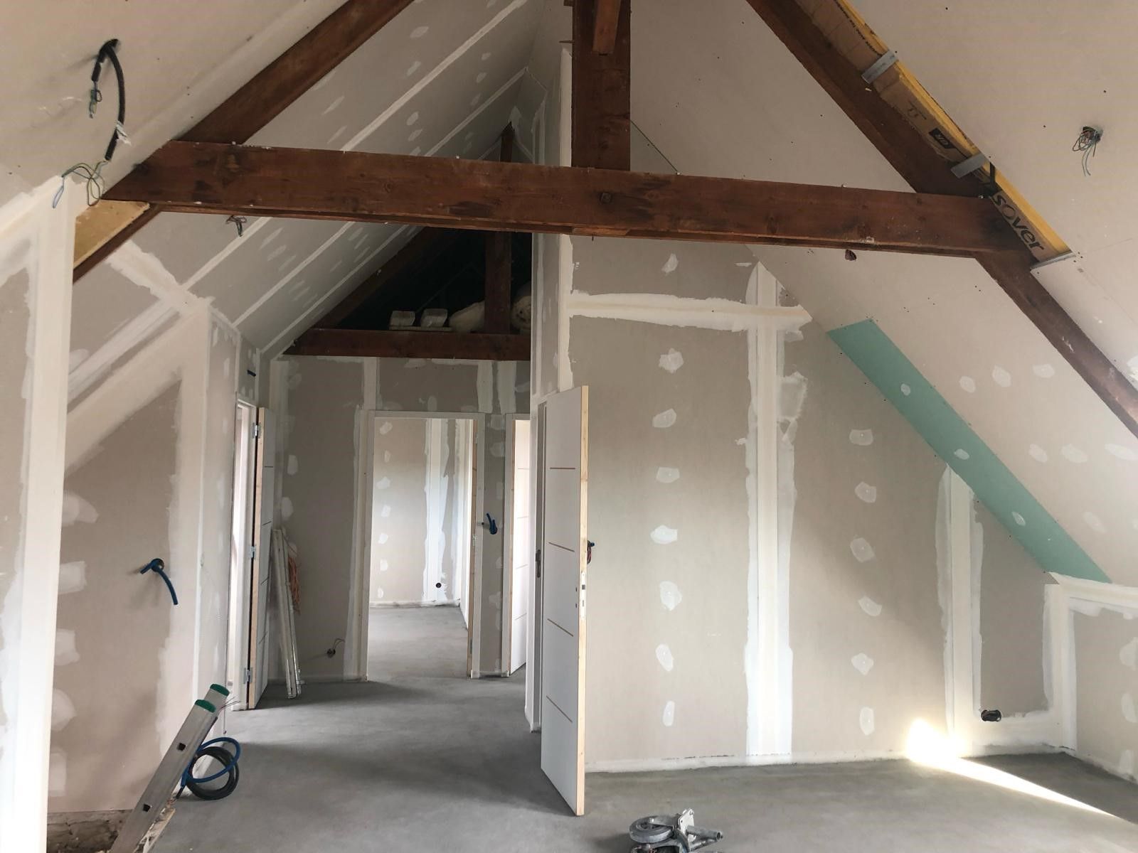 Chantier en cours d'aménagement de combles avec des poutres apparentes