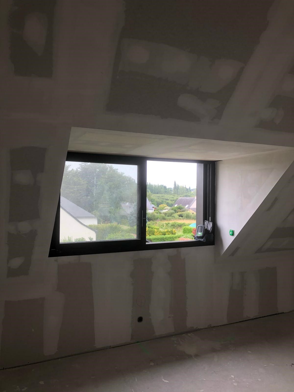 Fenêtre installée sous des combles avec des plaques de plâtre qui l'entourent
