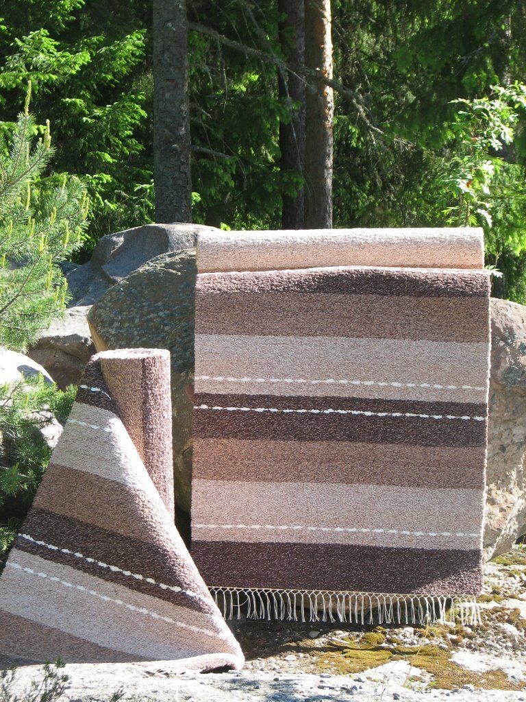 Kolme ruskeavalkoraidallista mattoa on pinottu päällekkäin