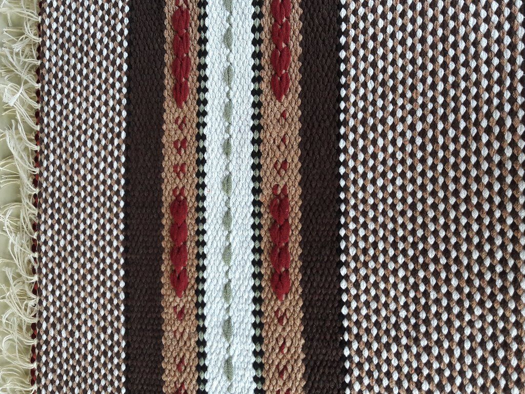 Lähikuva ruskeasta ja valkoisesta raidallisesta kankaasta, jossa on hapsut.