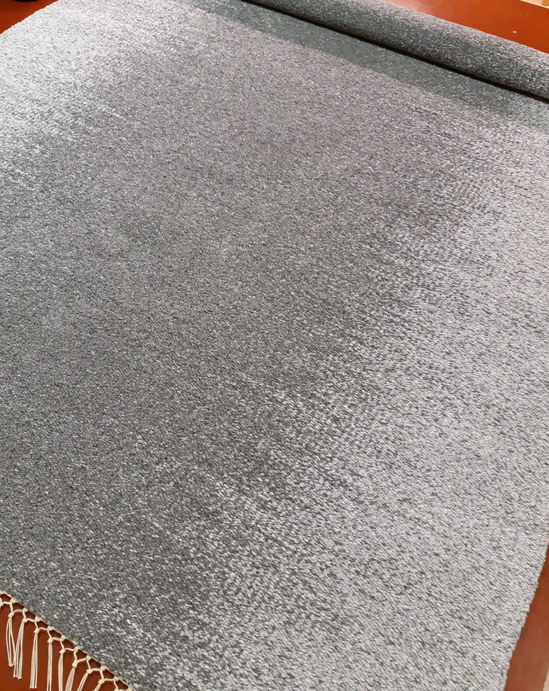 Lähikuva harmaasta matosta pöydällä