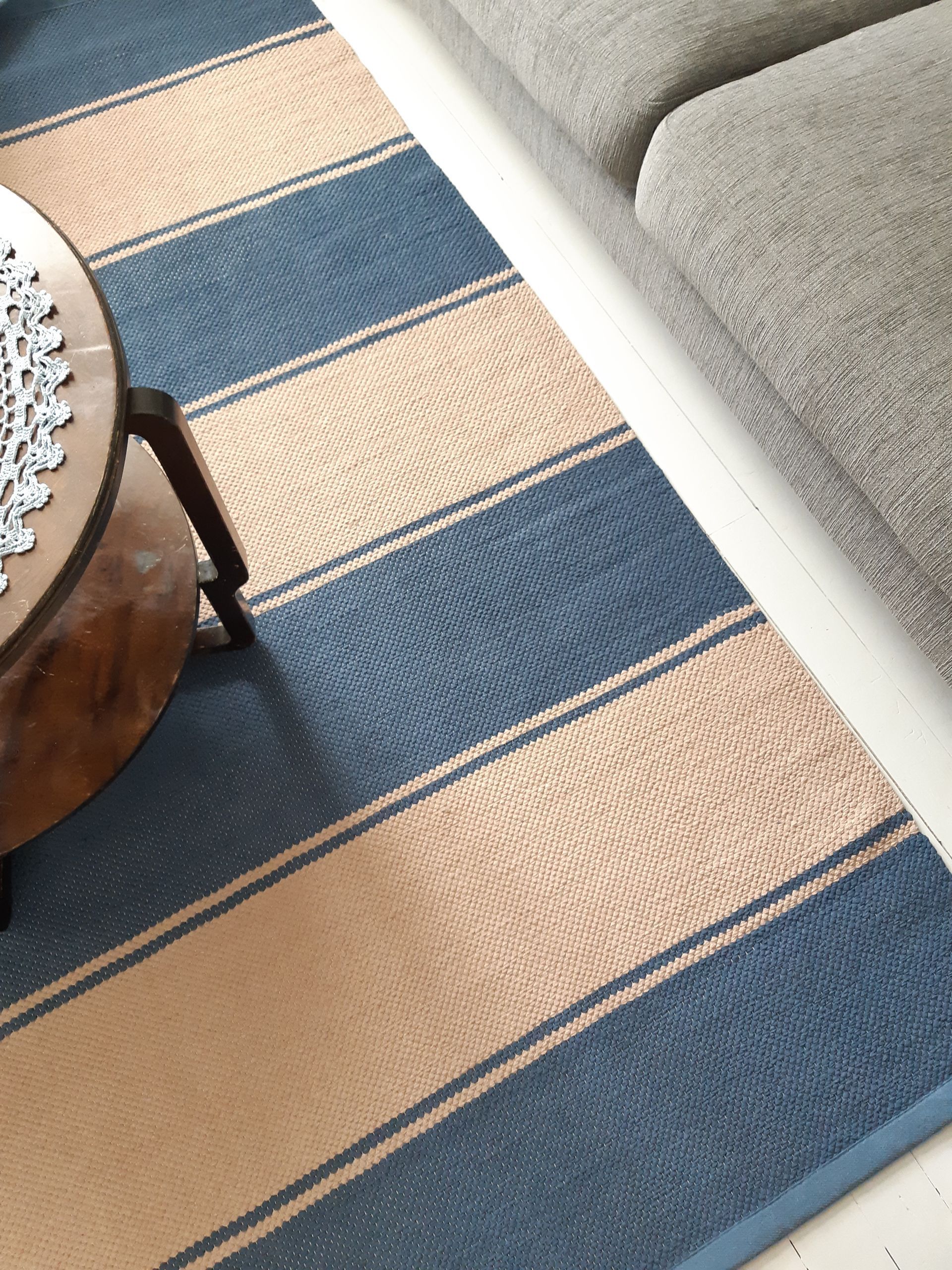 Lattialla sohvapöydän vieressä on sini-ruskea raidallinen matto