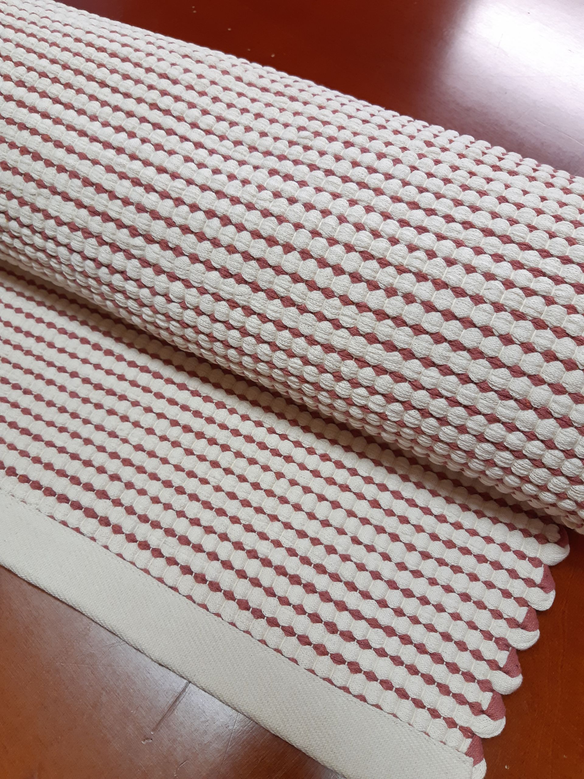 Punavalkoinen raidallinen matto on puisella pöydällä