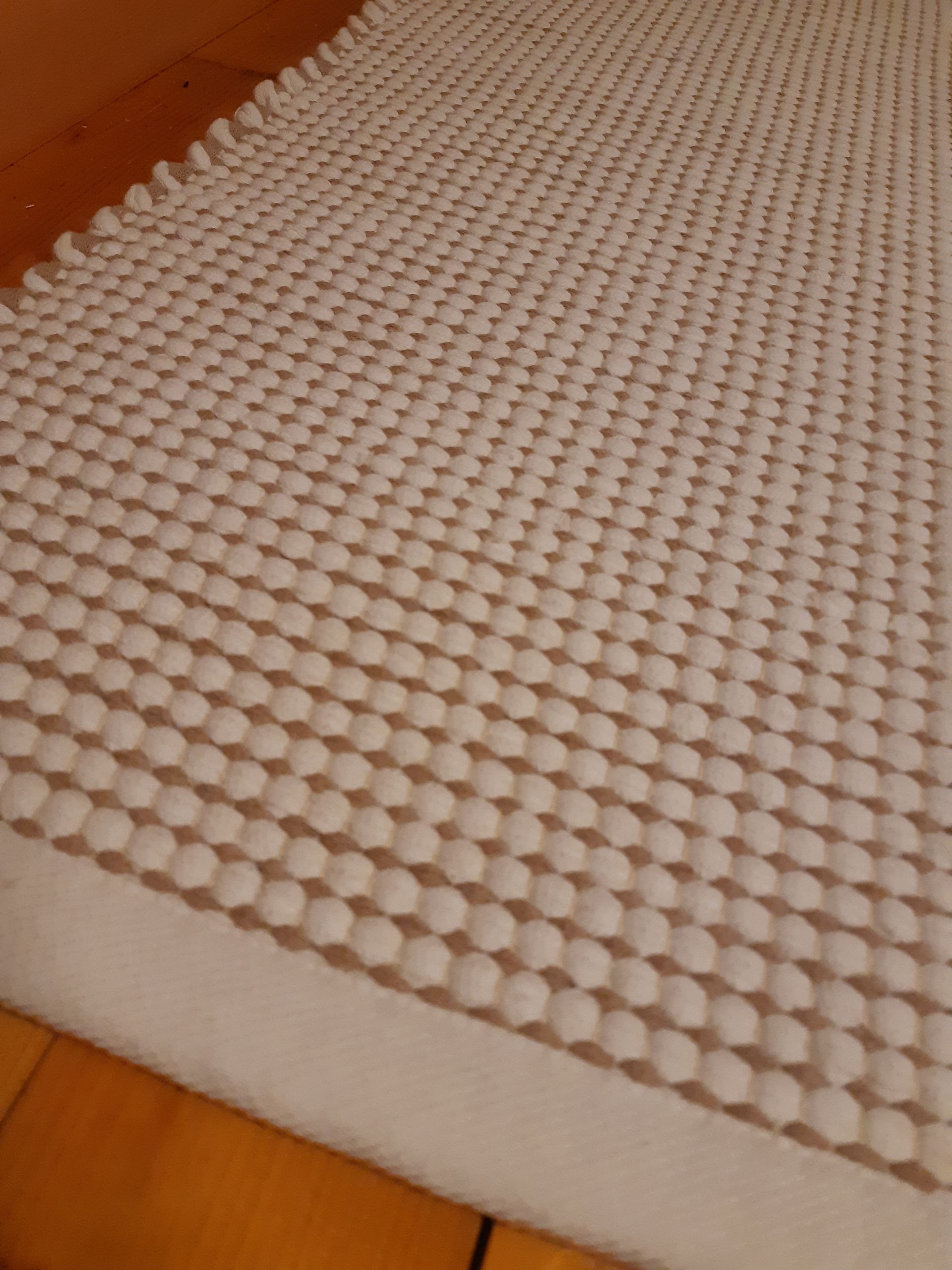 Valkoinen matto makaa puulattialla